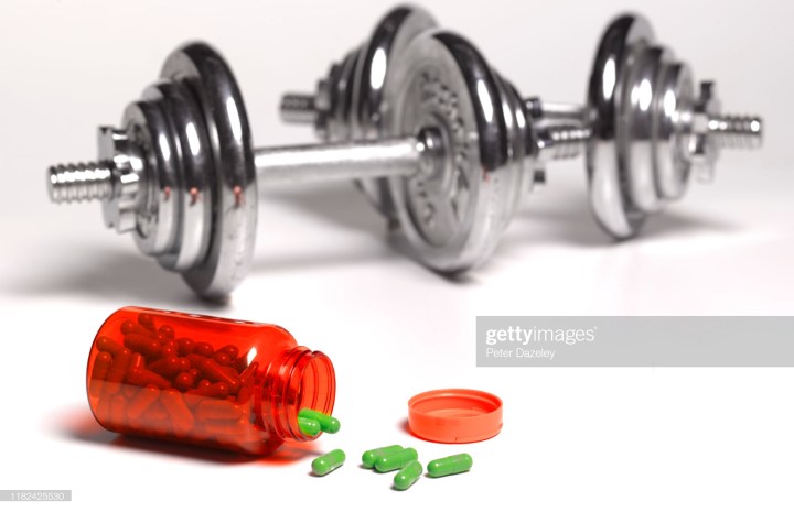 open bottle of pills in bodybuilding gym